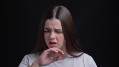 Siyah arka plan üzerine öksürük ve boğaz ağrısı sahip genç kilolu esmer beyaz kız portresi.