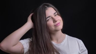 Saçlarını sallayarak ve sevinçle içine kamera siyah arka plan üzerine poz genç kilolu esmer beyaz kız portresi.