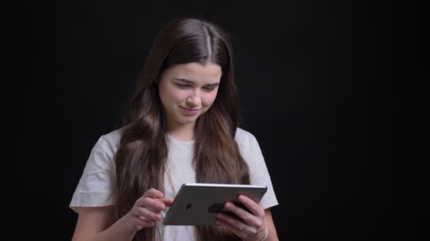 Portret van overgewicht brunette meisje glimlachend met groen scherm van tablet aan de achtergrond van de camera zwart. — Stockvideo