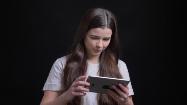 Portrait of young overweight brunette girl joyfully showing green screen of tablet to camera black background.