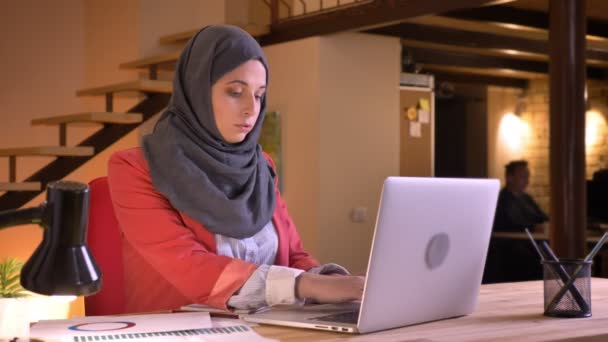 Retrato de close-up de jovem bela mulher de negócios muçulmana no hijab digitando no laptop dentro de casa no local de trabalho — Vídeo de Stock
