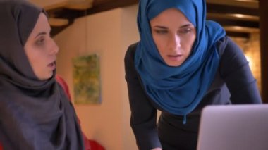 İki genç Arap kadın Ofis çalışanları verileri grafik üzerinde tartışırken hijabs içinde portre çekimleri