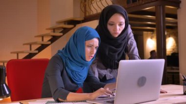 Genç güzel Müslüman işkadını gülüyor ve neşeyle kameraya bakarak bir takım içinde belgili tanımlık laptop üzerinde veri tartışırken closeup portresi