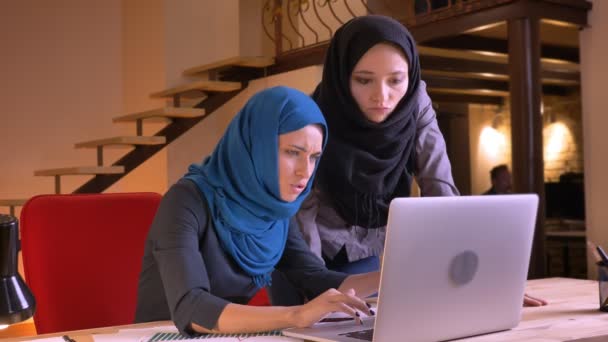 笑いと元気よくカメラを見てチームでのラップトップのデータを議論する若い美しいイスラム教徒の実業家のポートレート、クローズ アップ — ストック動画