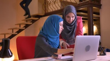 Duygusal laptop önünde bir konuyu tartışıyor sonra kameraya bakıyor ve gülümseyen iki genç güzel Müslüman mecaz closeup portresi