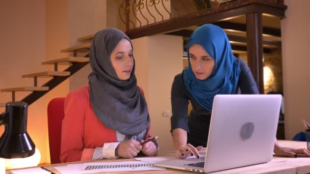 Closeup portret van jonge succesvolle moslim zakenvrouwen bespreken van de kwesties van het werk voor de laptop. De werkgever instrueren een Arabische werknemer — Stockvideo