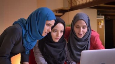 Dizüstü bilgisayar kullanıyorsanız ve heyecanlı ve mutlu sevinç işyeri kapalı üzerinde kutluyor üç neşeli Müslüman iş kadınları closeup portresi