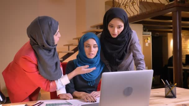 Närbild porträtt av tre unga muslimska affärskvinnor arbetar i team tillsammans med projekt inomhus på arbetsplatsen — Stockvideo