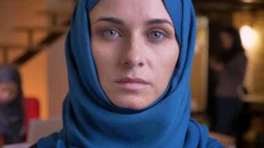 Genç Müslüman iş kadını gülümseyen ve doğruca kameraya güzel gri gözleri ile bakarak mavi hijab closeup portresi.