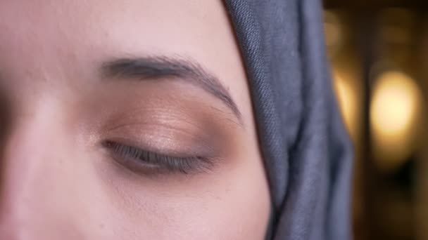 Closeup half-face portrait of young beautiful arabian female in gray hijab with brown eye looking straight at camera — Stock Video