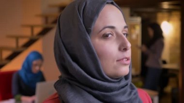 Kameraya dönüm ve neşeyle gülümseyen gri hijab Müslüman kadın çekici genç closeup portresi
