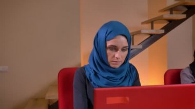 Portre, iki genç güzel Müslüman mecaz ofis dizüstü bilgisayarlarda yazarak hijabs içinde ateş. Bir başka Gazeteler geçmek istiyor