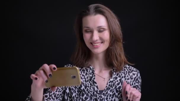 Gros plan portrait de jeune belle femme caucasienne ayant un appel vidéo au téléphone et saluant la caméra — Video