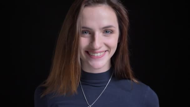 Detailní portrét mladé a štíhlé Černovlásky kavkazský dívky s úsměvem do kamery na černém pozadí. — Stock video