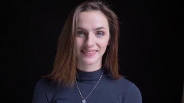 Yakın çekim içine kamera siyah arka plan üzerine naçizane izlerken genç ve ince esmer beyaz kız portresi.