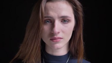 Yakın çekim ağlıyor ve siyah arka plan üzerine kamera içine izlerken üzgün genç ve ince esmer beyaz kız portresi.