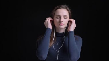Kulaklık müzik dinleme ve memnuniyeti ile siyah arka plan üzerine dans genç ve ince esmer beyaz kız portresi.