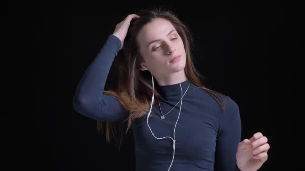 Πορτρέτο του νέους και λεπτή μελαχρινή Καυκάσιος κορίτσι να ακούτε μουσική στα ακουστικά και το χορό σε μαύρο φόντο. — Αρχείο Βίντεο
