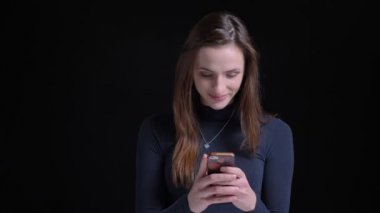 Yüzlerinde smartphone siyah arka plan üzerine içine izlerken genç ve ince esmer beyaz kız portresi.
