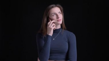 Siyah arka plan üzerinde dikkatle smartphone cep telefonu ile konuşurken genç ve ince esmer beyaz kız portresi.