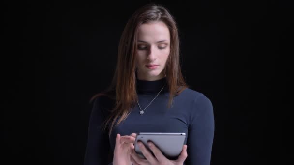 Retrato de joven y delgado morena caucásica chica mostrando la pantalla verde de la tableta a la cámara sobre fondo negro . — Vídeos de Stock