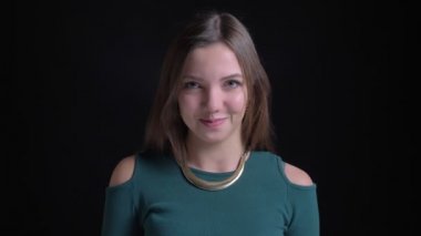 Utanarak içine kamera siyah arka plan üzerinde gülümseyen genç esmer beyaz kız portresi.