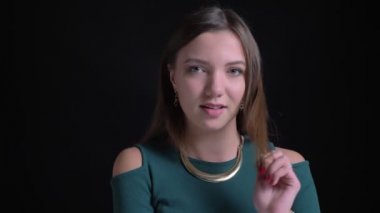 Cidden kameraya izliyor ve saçlarını flirtingly siyah arka plan üzerine sabitleme genç esmer beyaz kız portresi.
