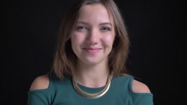 Sevinçle başını sallayarak ve siyah arka plan üzerine kamera içine izlerken genç esmer beyaz kız portresi yakın çekim.