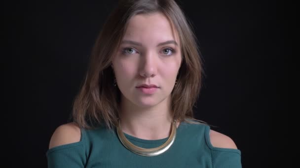 Fiatal barna kaukázusi lány fordult a fejét elgondolkodva, hogy nem ért egyet, a fekete háttér közelről portréja. — Stock videók