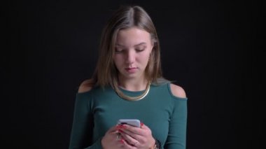 Siyah arka plan üzerine smartphone içine izlerken gülmekten genç ve güzel esmer beyaz kız portresi.