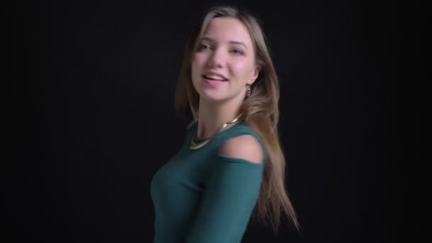 Portrét mladé Černovlásky kavkazský dívky točí kolem šťastně a ukázal jí prstem na kameru na černém pozadí. — Stock video