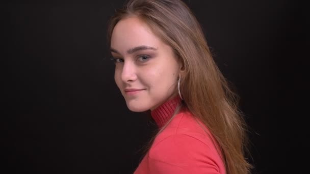 Closeup portrait of young caucasian female model turning and looking at camera smiling and tossing her hair — Stock Video