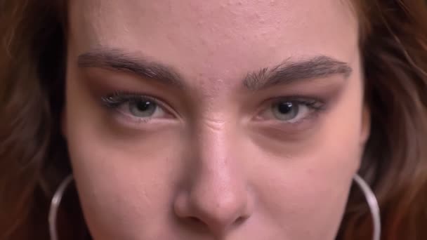 Primo piano ritratto di giovane bella faccia femminile caucasica con gli occhi grigi facendo uno sguardo selvaggio alla macchina fotografica — Video Stock