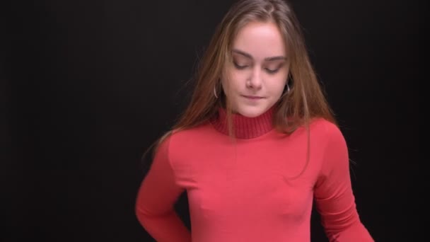 Närbild porträtt av unga kaukasiska kvinnlig modell fastställande hennes hår och med armarna korsade över bröstet titta på kameran med blyghet — Stockvideo