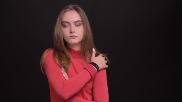 Κινηματογράφηση σε πρώτο πλάνο το πορτρέτο νεαρό όμορφο καυκάσιος γυναίκα μοντέλο ποζάρει μπροστά από την κάμερα που αγκαλιάζει τον εαυτό της και να αγγίζει τα μαλλιά — Αρχείο Βίντεο