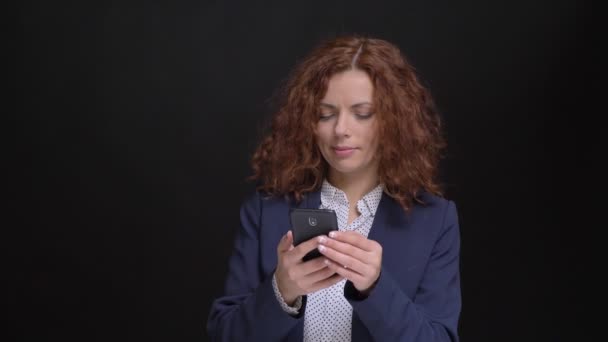 Nahaufnahme Porträt einer erwachsenen kaukasischen Frau mit rotgelockten Haaren, die das Telefon benutzt und auf Posts in den sozialen Medien reagiert — Stockvideo