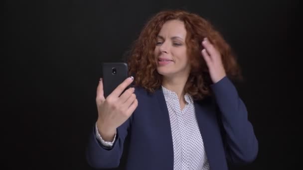 Closeup portret van volwassen Kaukasische roodharige vrouw met een casual video-oproep op de telefoon en tonen iets achter haar — Stockvideo