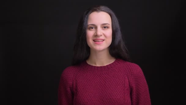 Closeup portrait of young attractive caucasian black-haired female raising her head and smiling while looking straight at camera — Stock Video