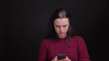 Yetişkin neşeli beyaz kadın manifatura telefon ve mutlu bir şekilde kamera önünde gülümseyen closeup portresi