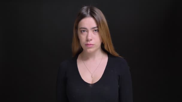 Nahaufnahme Porträt der jungen charmanten kaukasischen Frau mit langen blonden Haaren, die geradeaus in die Kamera schaut, mit Hintergrund isoliert auf schwarz — Stockvideo