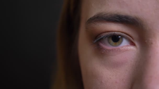 Closeup half-face portret van jonge mooie Kaukasische vrouwelijke gezicht met groen oog meteen kijken naar camera — Stockvideo