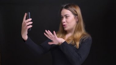 Portre rahat konuşma ve arka plan üzerinde siyah izole ile el hareketi telefonda görüntülü görüşme sahip genç güzel beyaz kadın portresi