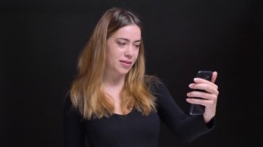 Portre rahat konuşmaya ve güle güle kamera önünde sallayarak telefonda görüntülü görüşme sahip genç güzel beyaz kadın portresi