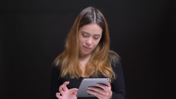 Nahaufnahme Porträt einer jungen schönen kaukasischen Frau, die auf dem Tablet tippt, dann in die Kamera schaut und lächelt — Stockvideo