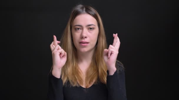 Closeup portrait of young beautiful caucasian female being anxious and having her fingers crossed in hope looking at camera — Stock Video