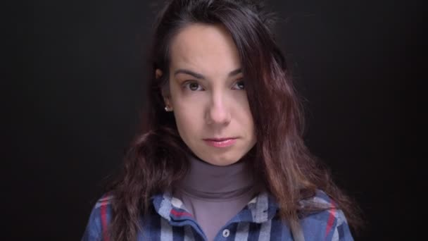 Retrato cerrado de joven hermosa cara femenina caucásica con ojos marrones mirando directamente a la cámara con fondo aislado en negro — Vídeos de Stock