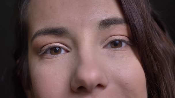 Retrato de close-up de jovem bonito rosto feminino caucasiano com olhos castanhos olhando diretamente para a câmera — Vídeo de Stock