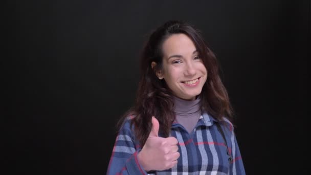 Detailní portrét mladého veselá Kavkazský žena ukazuje palcem a usmíval se při pohledu na fotoaparát — Stock video