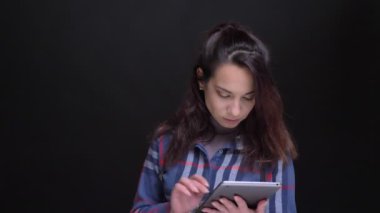 Tablet kullanarak sonra kameraya bakıyor ve gülümseyen genç güzel beyaz kadın portresi portre