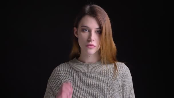 Primer plano retrato de joven modelo femenina caucásica encantadora mirando recto y fijando su pelo posando delante de la cámara — Vídeo de stock